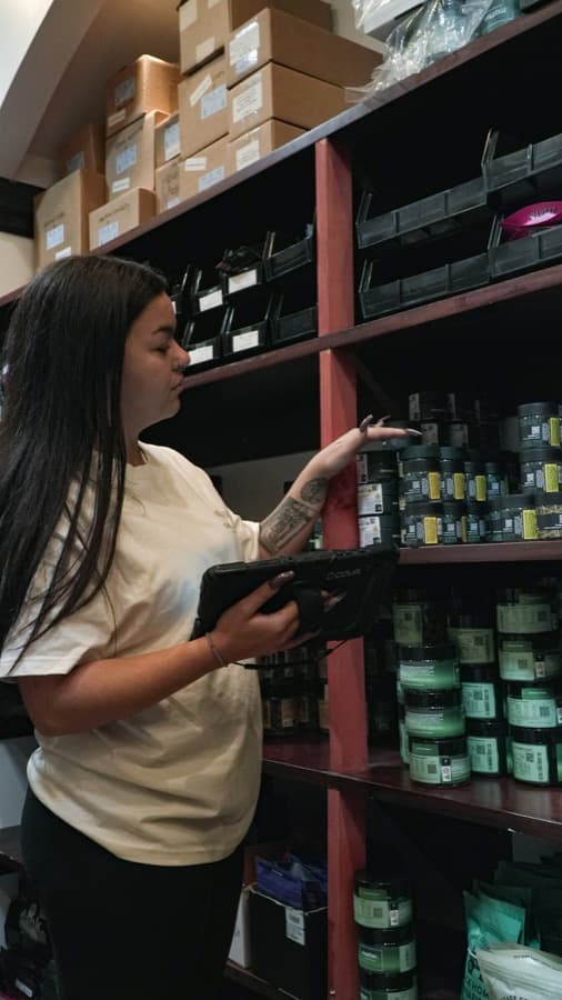 Operaria revisa el inventario con una tableta entre estanterías